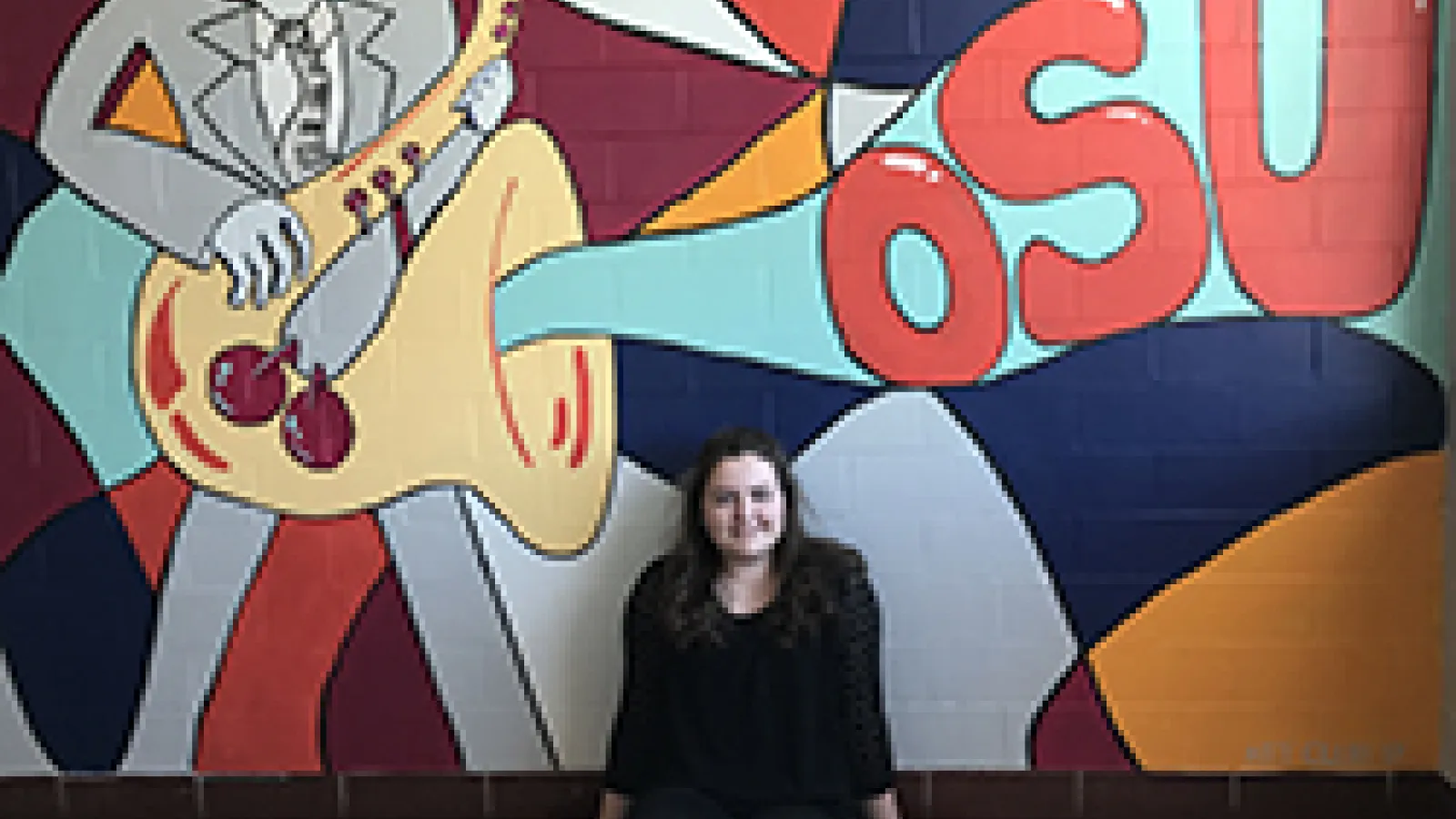 Audrey Watkins poses with her mural in Hughes Hall